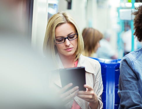 Businesswoman using digital tablet on train.