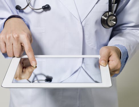 Photo of hands of a doctor touching a tablet