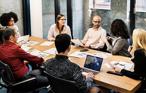 Les employés discutent de quelque chose lors d’une réunion d’affaires sur des ordinateurs portables et des documents autour de la table.