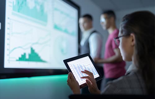 Femme d’affaires regardant des graphiques sur une tablette numérique lors d’une réunion d’affaires
