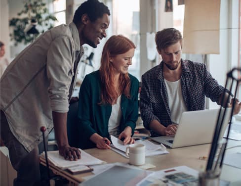 Three people around a desk looking at data for insights about improving management processes