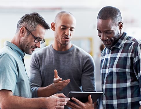 Three men discussing using a tablet device.
