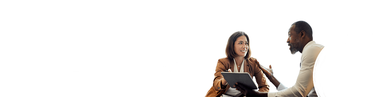 A woman and a man are engaged in a professional conversation in an office setting, the woman holding a tablet and smiling as the man gestures with his hand, discussing readiness for the M-19-21 Directive deadline.