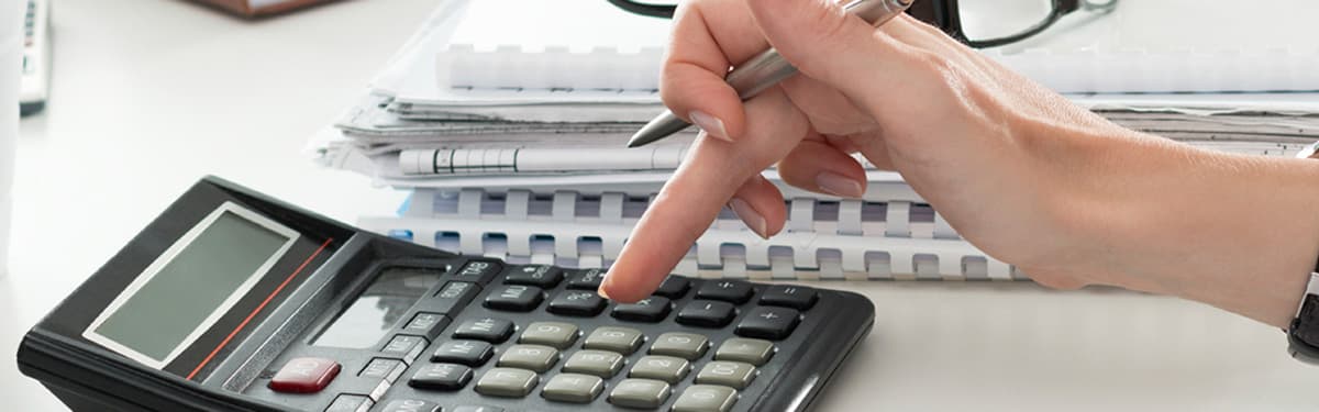 Close up of woman holding a pen while making calculations. Paper in background