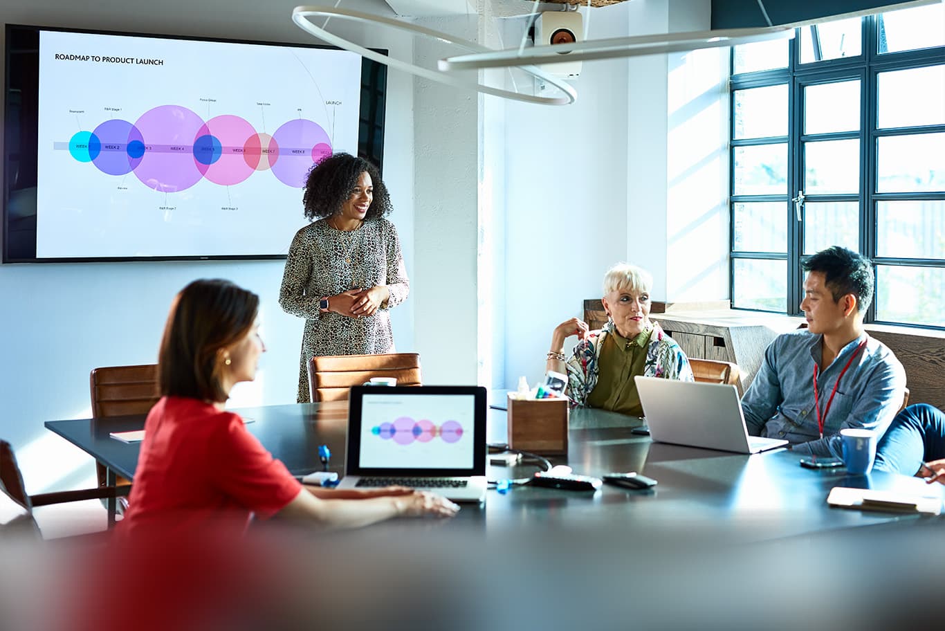 Team members gathered in conference room using interactive white board for presentation