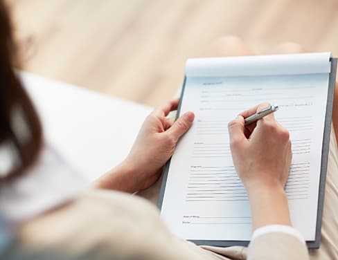 Over the shoulder of a woman writing on a notepad