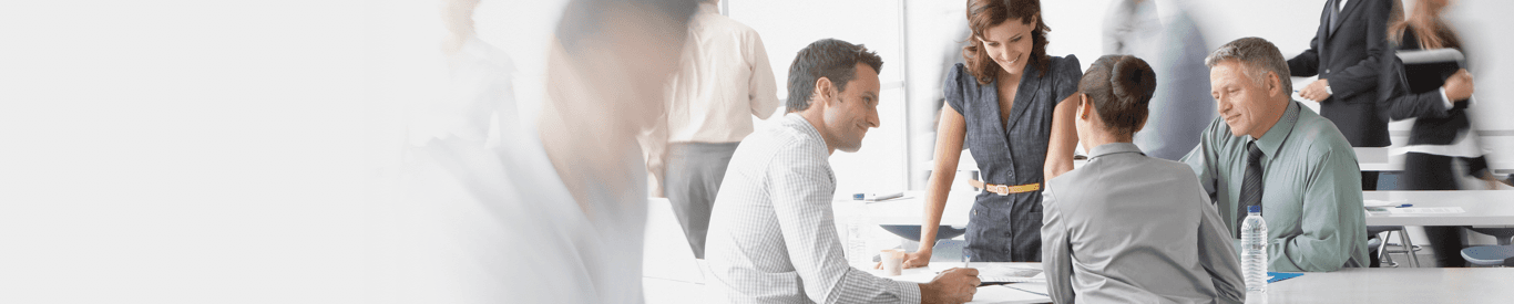 Woman at desk with computer and paperwork in hand