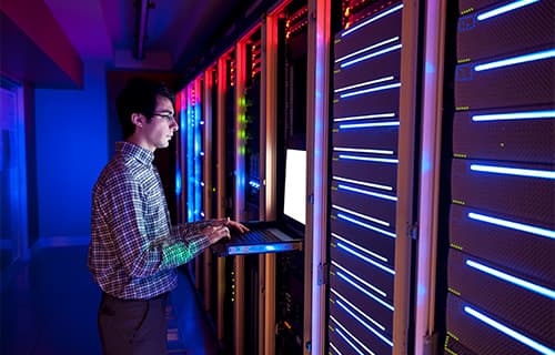 IT server room with specialist working on computer
